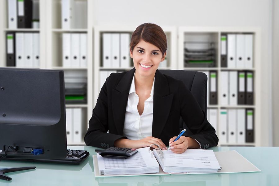Portrait of confident female accountant writing on documents at desk in office
Portrait,Of,Confident,Female,Accountant,Writing,On,Documents,At,Desk